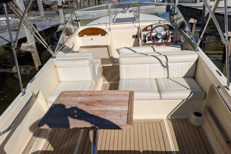Slide: The Image of 2017 Rossiter R23 boat interior with beige seating and wooden table. - 4