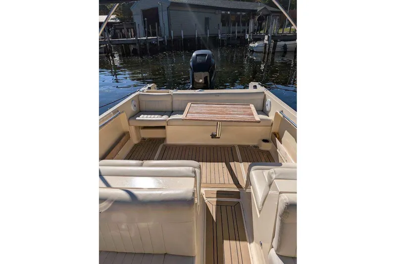 Slide: The Image of 2017 Rossiter R23 boat interior with seating and wooden table, docked by a waterfront. - 5