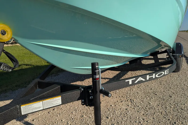 Slide: The Image of 2026 Tahoe T16 boat on trailer, light blue hull, parked on gravel road. - 67