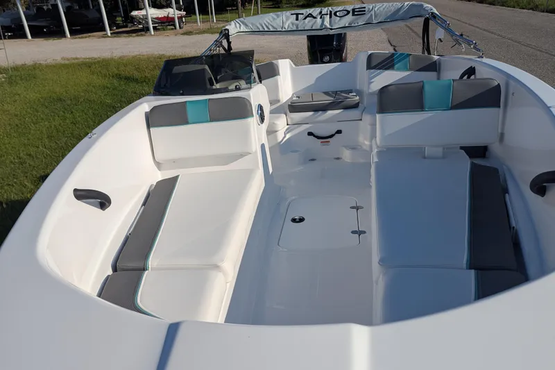 Slide: The Image of 2026 Tahoe T16 boat interior with white and teal seating, parked outdoors. - 68