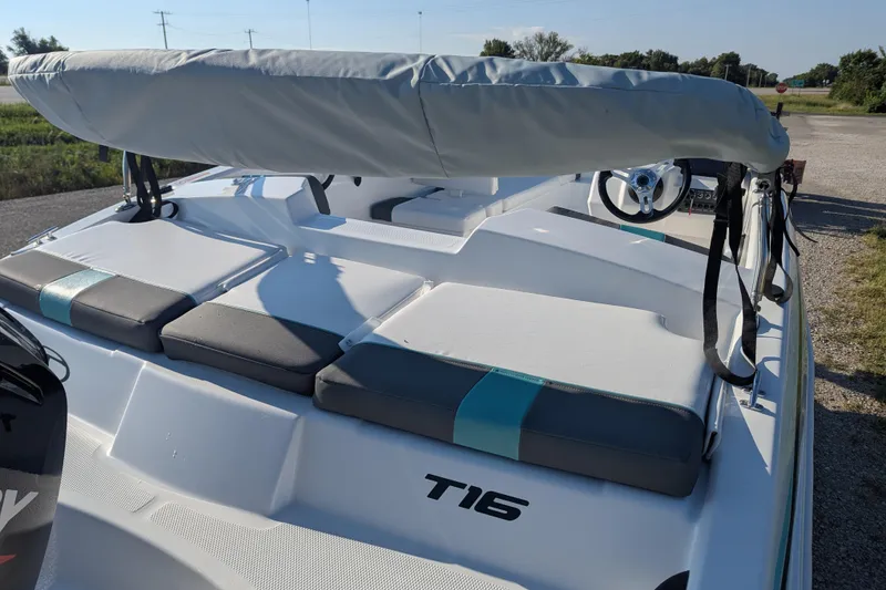 Slide: The Image of 2026 Tahoe T16 boat with cushioned seating and steering wheel, parked outdoors. - 71
