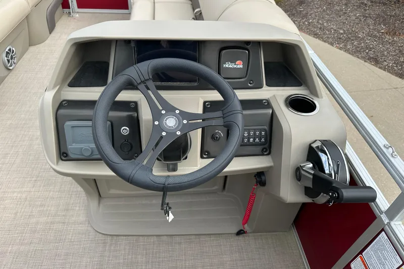 Slide: The Image of 2025 Sun Tracker Party Barge 22 DLX steering console with controls and cup holder. - 4