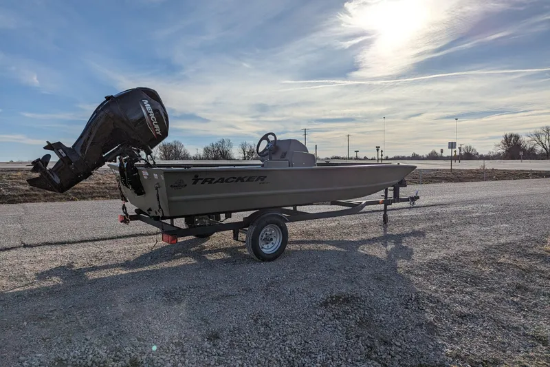Slide: The Image of 2026 Tracker Grizzly 1648 SC boat on trailer, parked on gravel under a bright sky. - 32