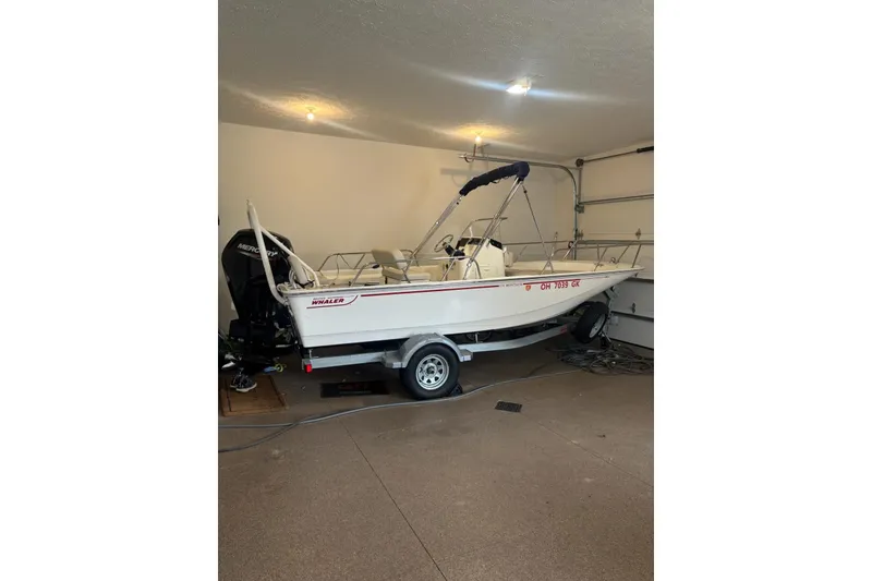 Slide: The Image of 2023 Boston Whaler 170 Montauk boat in garage, on trailer, with outboard motor. - 1