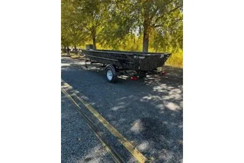 Slide: The Image of 2026 Tracker Grizzly 1754 Utility boat on trailer, parked under trees. - 2
