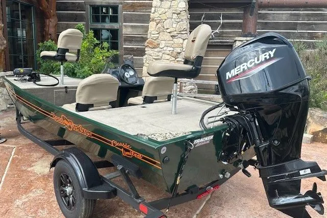 Slide: The Image of 2026 Tracker Bass Tracker Classic Limited boat with Mercury engine, parked outdoors. - 2