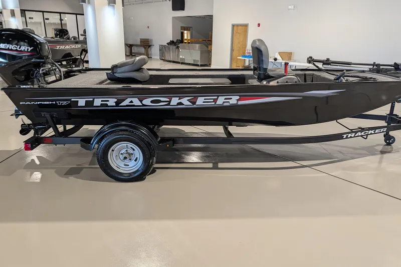 Slide: The Image of 2025 Tracker Panfish 17 boat on trailer in showroom, featuring sleek black design. - 41