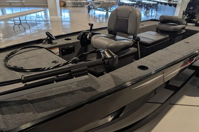 Slide: The Image of 2025 Tracker Panfish 17 boat interior with seating and controls in showroom. - 44
