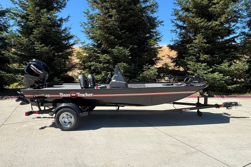 The Image of 2026 Tracker Bass Tracker Classic XL boat on trailer, parked outdoors with trees in background. - 0