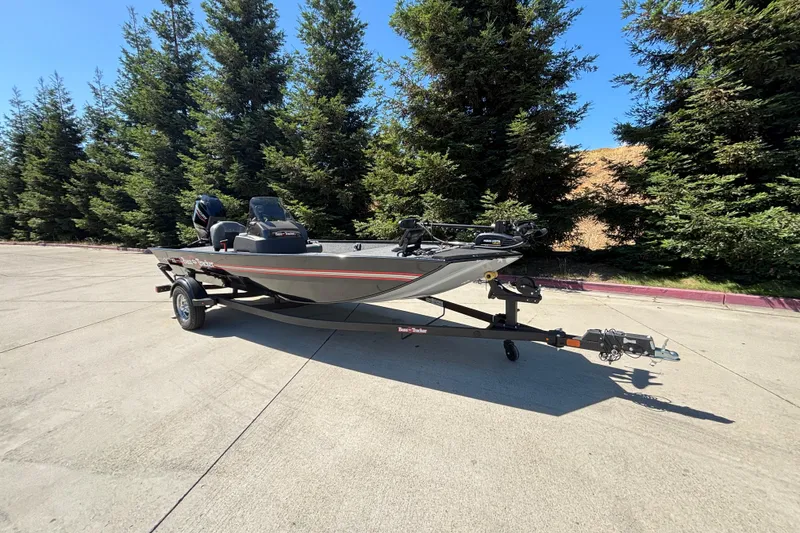 Slide: The Image of 2026 Tracker Bass Tracker Classic XL boat on trailer, parked near trees. - 2