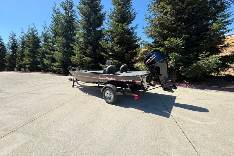 Slide: The Image of 2026 Tracker Bass Tracker Classic XL boat on trailer, parked near trees. - 3