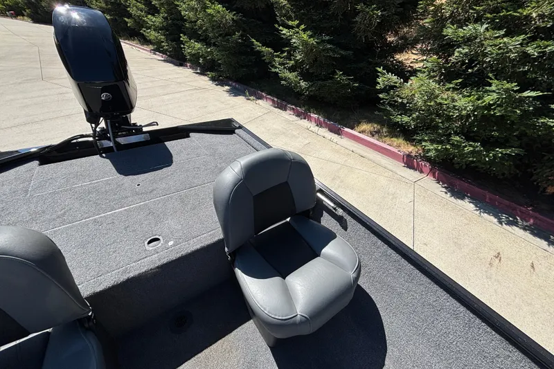 Slide: The Image of 2026 Tracker Bass Tracker Classic XL boat with gray seating and motor, parked near trees. - 8