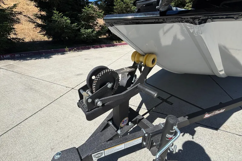 Slide: The Image of 2026 Tracker Bass Tracker Classic XL boat trailer with winch and roller on pavement. - 39
