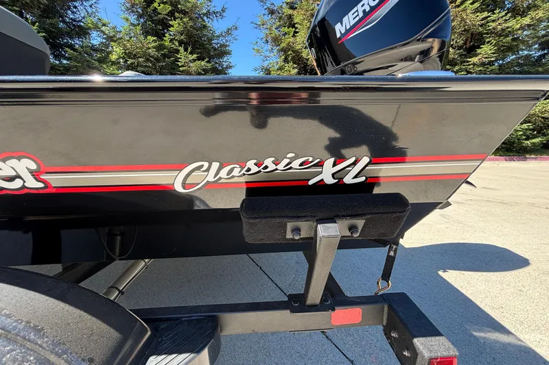 Slide: The Image of 2026 Tracker Bass Tracker Classic XL boat with Mercury engine, parked outdoors. - 38