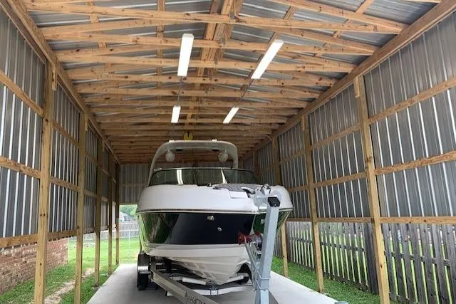 Slide: The Image of 2018 Rinker 29QX boat stored in a metal shed on a trailer. - 5