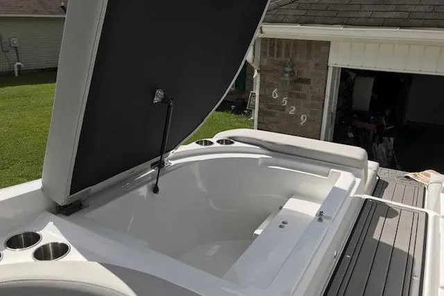 Slide: The Image of 2018 Rinker 29QX boat with open storage compartment in a residential driveway. - 12