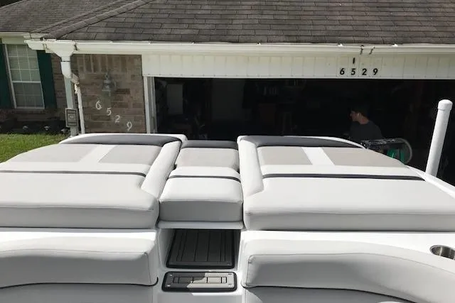 Slide: The Image of 2018 Rinker 29QX boat with cushioned seating, parked in front of a garage. - 11