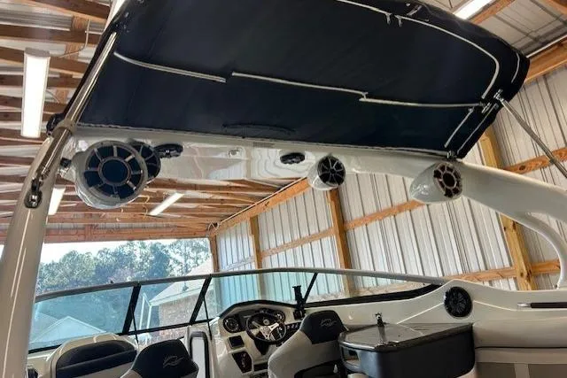 Slide: The Image of 2018 Rinker 29QX boat interior with speakers and canopy in a wooden boathouse. - 3