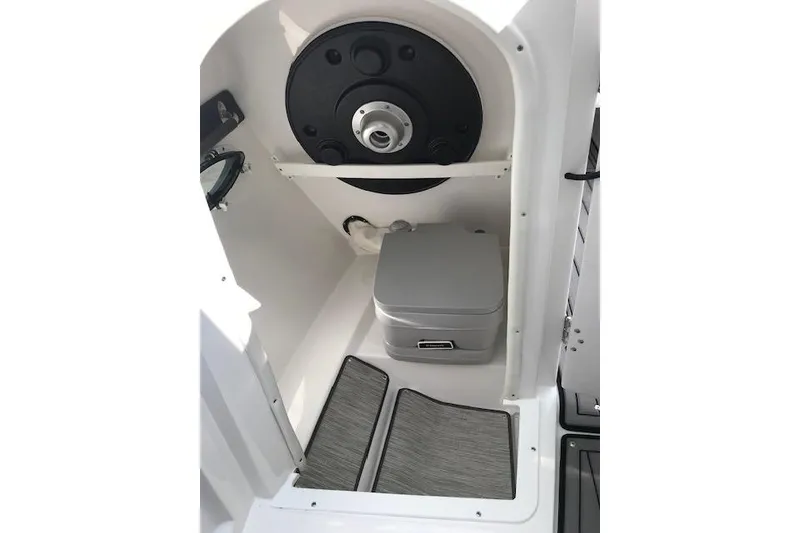 Slide: The Image of 2018 Rinker 29QX boat interior with compact toilet and storage area. - 15