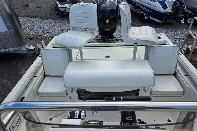 Slide: The Image of 2022 Ranger RB200 boat interior with white seating and motor, parked on gravel. - 18