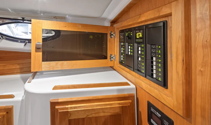 Slide: The Image of Electrical panel inside 2026 Back Cove 340 boat, featuring wooden cabinetry and modern controls. - 14