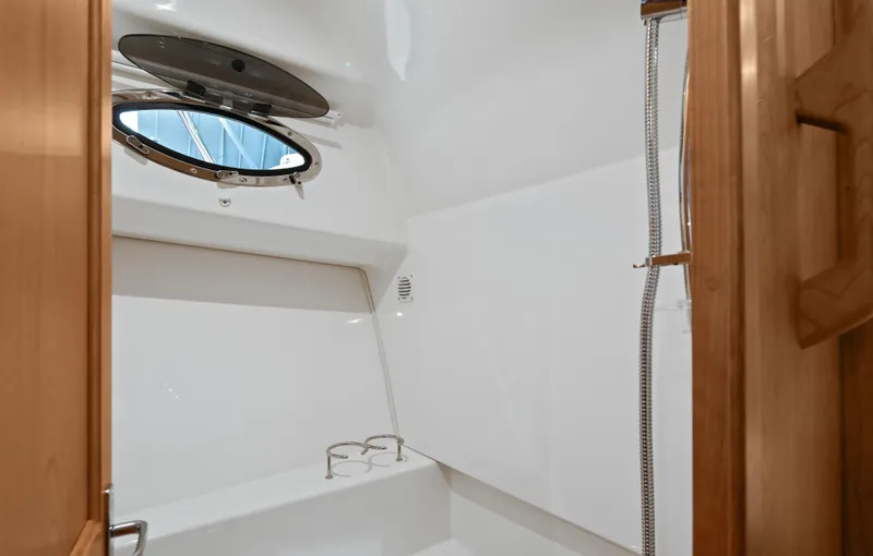 Slide: The Image of 2026 Back Cove 340 boat interior with sleek white shower and porthole window. - 19