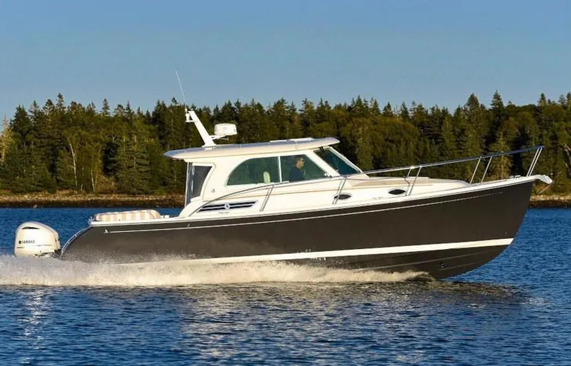 Slide: The Image of 2026 Back Cove 340 boat cruising on a serene lake with forested background. - 23