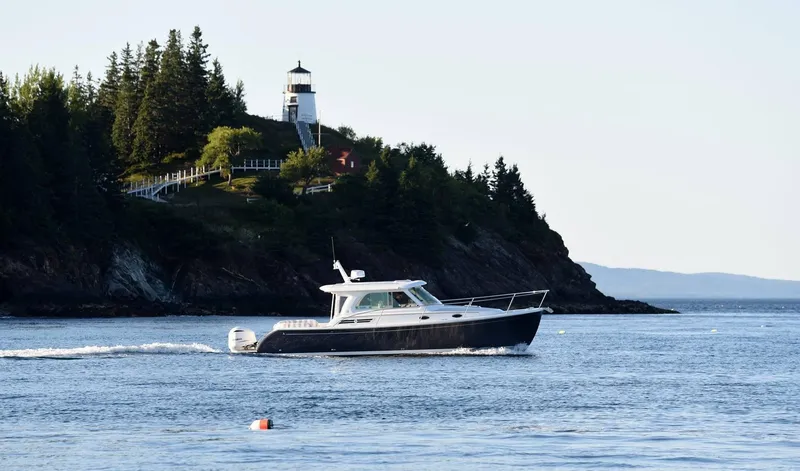 Slide: The Image of Back Cove 340 boat cruising near a scenic lighthouse, 2026 model. - 25