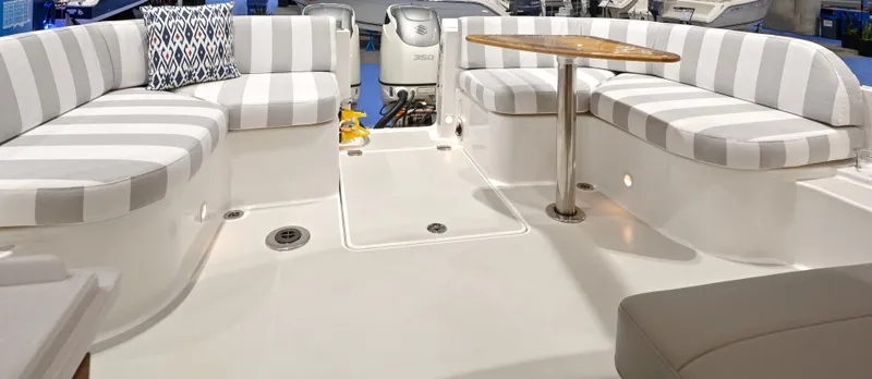 Slide: The Image of 2026 Back Cove 340 boat interior with striped seating and a round table. - 5