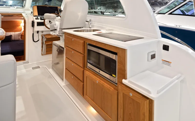 Slide: The Image of 2026 Back Cove 340 yacht interior with kitchenette, featuring microwave, sink, and wooden cabinetry. - 9