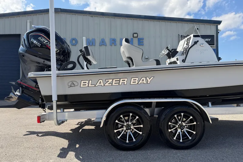 Slide: The Image of 2026 Blazer 675 Ultimate Bay boat on trailer, parked outside a marine shop. - 4