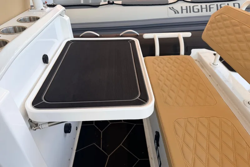 Slide: The Image of Highfield Sport 660 boat interior with tan quilted seats and foldable table, 2026 model. - 14