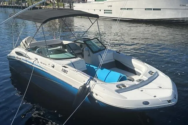 The Image of 2019 Hurricane SunDeck 2410 OB boat docked on calm water with canopy. - 0