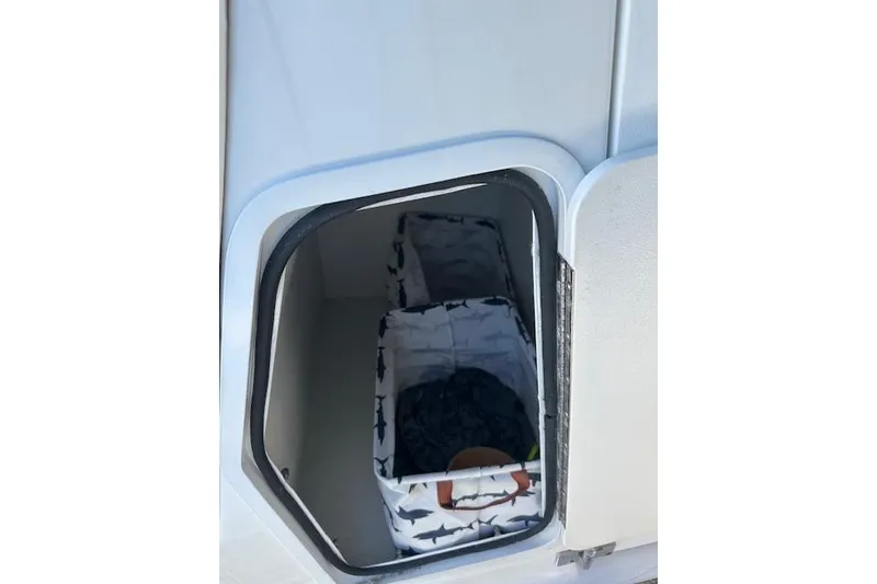 Slide: The Image of Storage compartment on a 2019 Hurricane SunDeck 2410 OB boat with shark-patterned bags. - 23