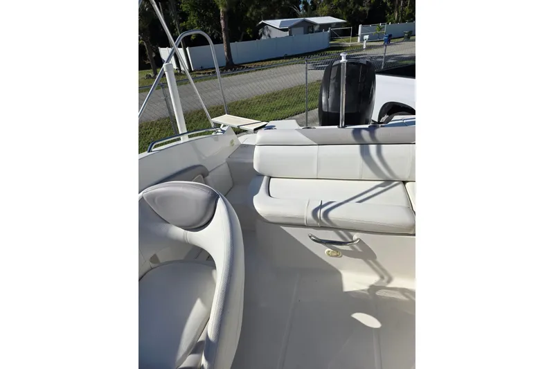 Slide: The Image of 2013 Bayliner 190 Deck Boat interior with white seating and outdoor view. - 12