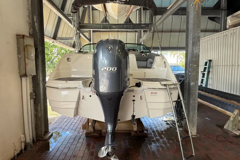 Slide: The Image of 2023 NauticStar 243 DC boat with Yamaha 200 engine in a covered storage area. - 12
