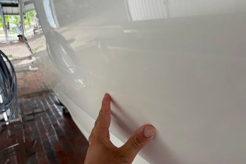 Slide: The Image of 2023 NauticStar 243 DC boat hull with a hand inspecting the surface. - 19