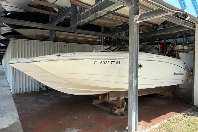 Slide: The Image of 2023 NauticStar 243 DC boat stored in a covered marina, side view. - 2
