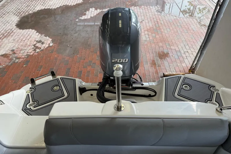 Slide: The Image of 2023 NauticStar 243 DC boat with powerful 200 HP engine, docked on brick surface. - 23