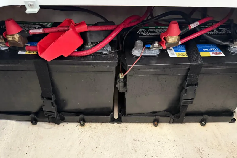 Slide: The Image of Batteries in a 2023 NauticStar 243 DC boat, secured with straps and red cables. - 27