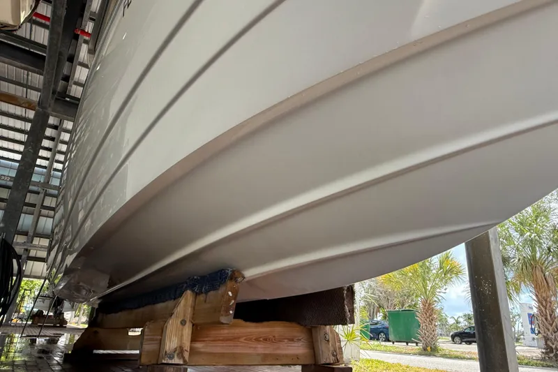 Slide: The Image of 2023 NauticStar 243 DC boat hull on wooden support in storage facility. - 3