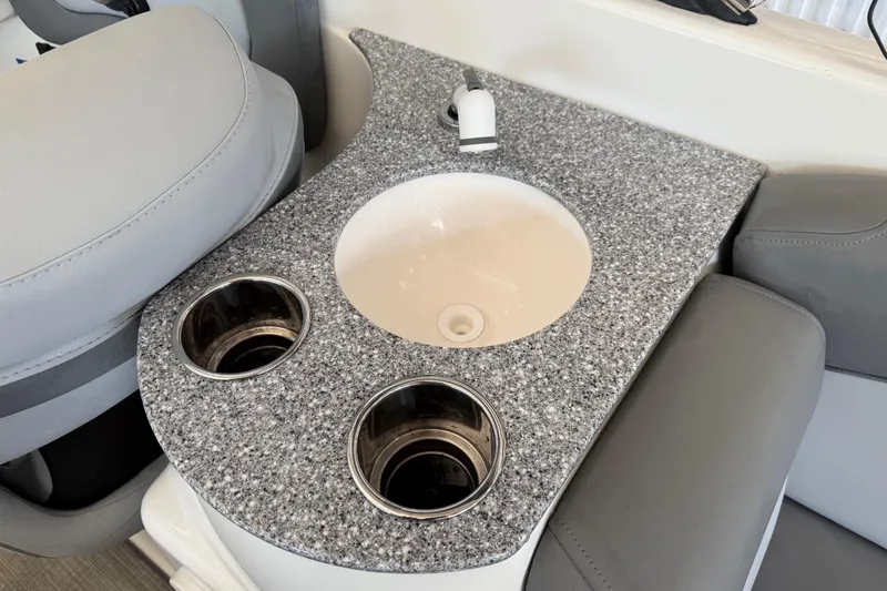 Slide: The Image of 2023 NauticStar 243 DC boat interior with granite countertop, sink, and cup holders. - 30