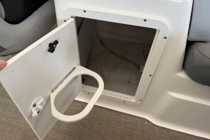 Slide: The Image of Open storage compartment on 2023 NauticStar 243 DC boat with cup holder. - 31