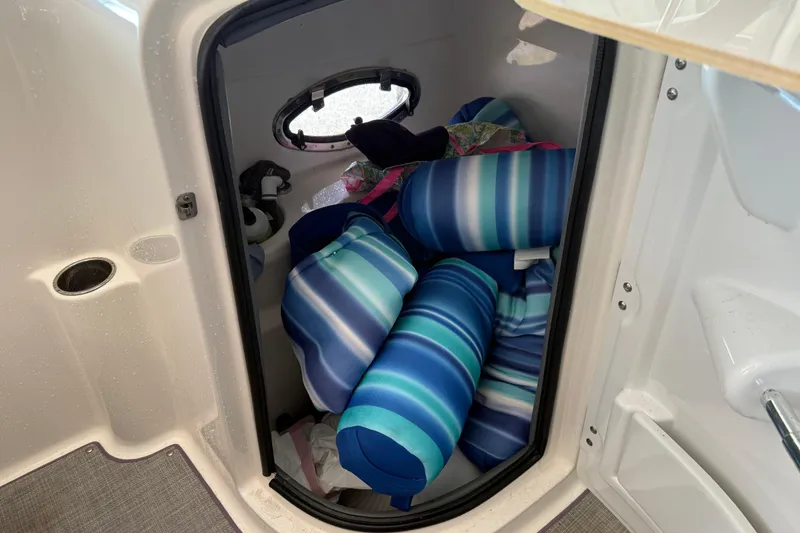 Slide: The Image of Storage compartment in 2023 NauticStar 243 DC boat with striped cushions. - 35