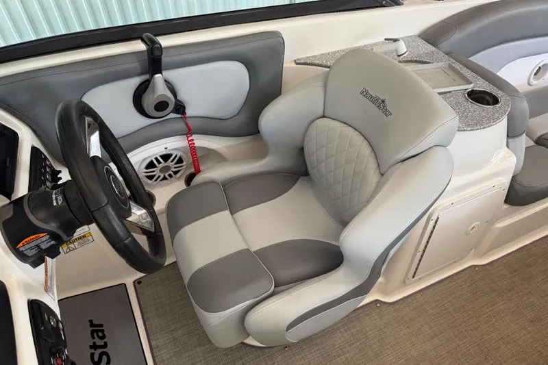 Slide: The Image of 2023 NauticStar 243 DC boat interior with steering wheel and cushioned captain's chair. - 37