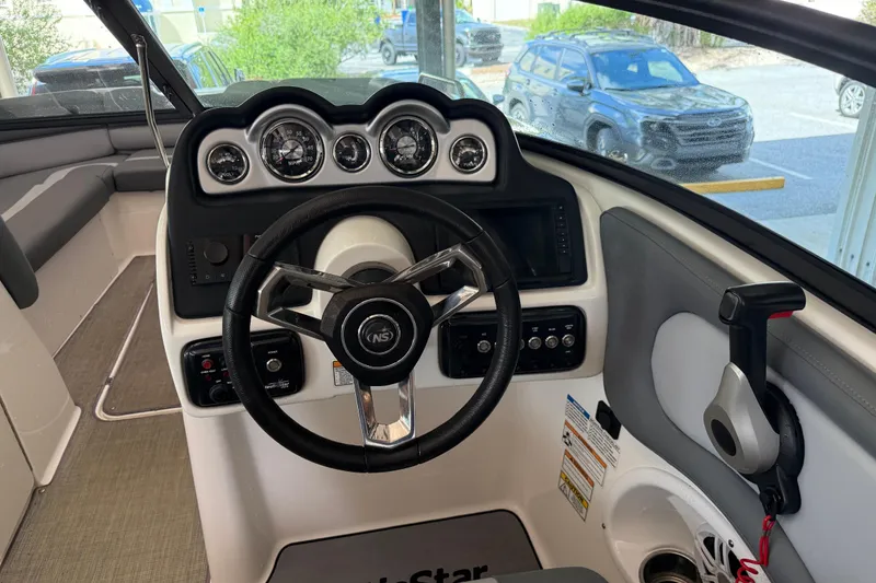 Slide: The Image of 2023 NauticStar 243 DC boat dashboard with steering wheel and control panel. - 39