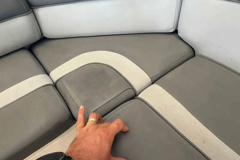 Slide: The Image of Gray and white seating on 2023 NauticStar 243 DC boat, with hand touching upholstery. - 48