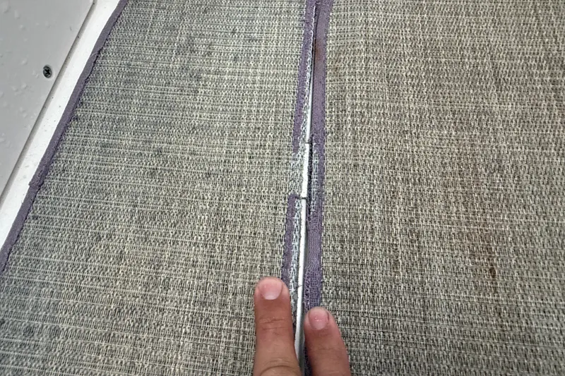 Slide: The Image of Close-up of 2023 NauticStar 243 DC boat carpet seam with fingers pointing. - 59