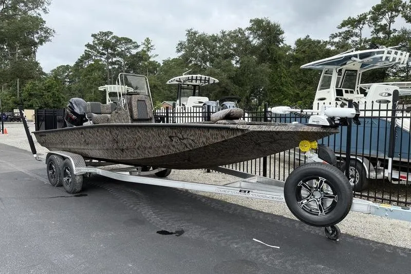 Slide: The Image of 2026 Xpress H22B Bay boat on trailer, parked outdoors near other boats. - 2