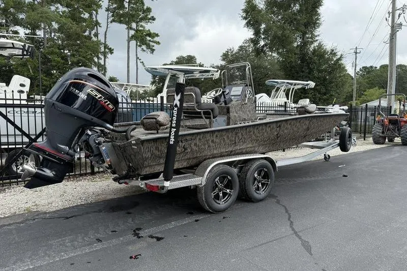 Slide: The Image of 2026 Xpress H22B Bay boat on trailer with powerful outboard motor, parked outdoors. - 3